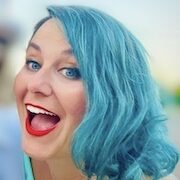 Smiling woman with blue hair, blue eyes, and red lips