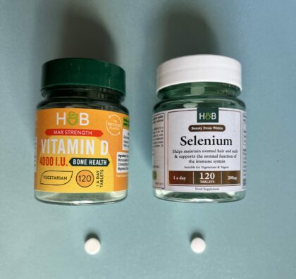 Bottles of Vitamin D and Selenium with one of their pills below them. The pills look identical in shape size and colour.